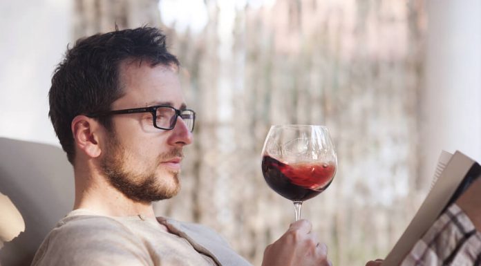 5 bebidas para relaxar depois de um dia estressante Homem com taça de vinho